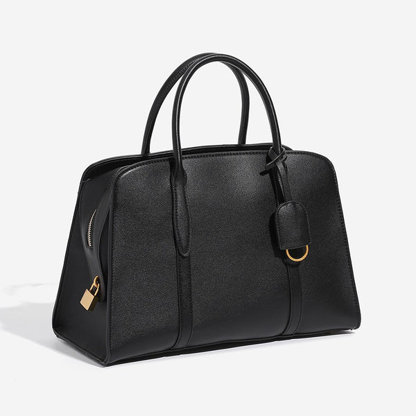 Structured trapezoid Boston satchel bag with dual top handles, gold-tone lock charm, and top zip closure, detail view 3