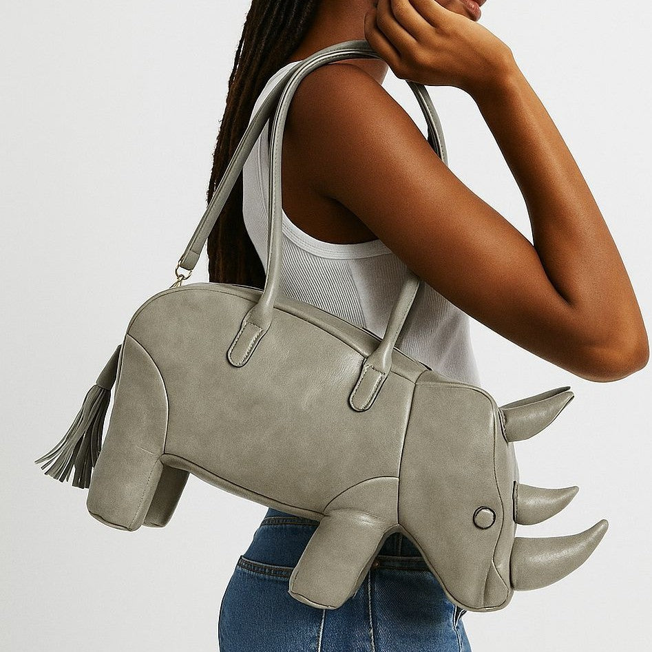 Rhinoceros-shaped 3D structured handbag with sculpted horns, four legs, tassel tail, twin top handles, and detachable, front