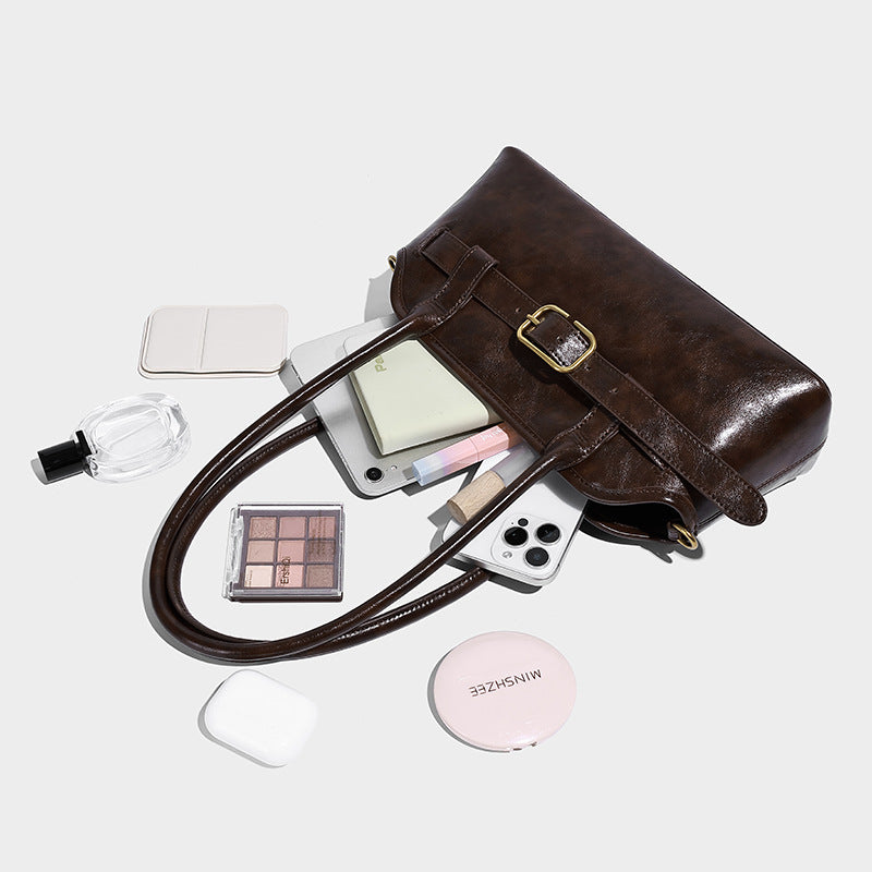 Strukturierte Henkeltasche in Dunkelbraun mit Oil-Wax-Finish, vorderer Gürtelschnalle, goldfarbenen Beschlägen, zwei Tragegriffen und, Detailansicht