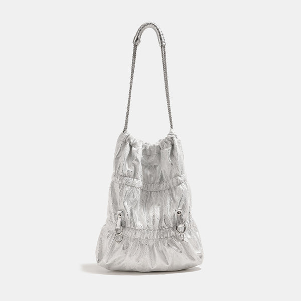 Slouchy lace-overlay bucket bag with silver chain strap, draped chain detail, shell charms, and drawstring top closure