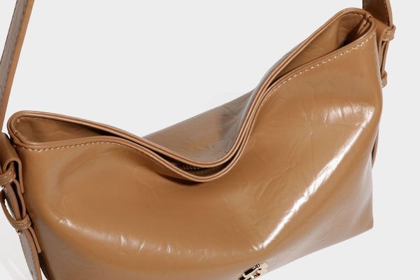 Lässig fallende Hobo-Schultertasche mit offenem Oberteil aus glänzender, karamellbrauner Lederoptik, mit Logo-Beschlägen in Goldoptik und langem, verstellbarem