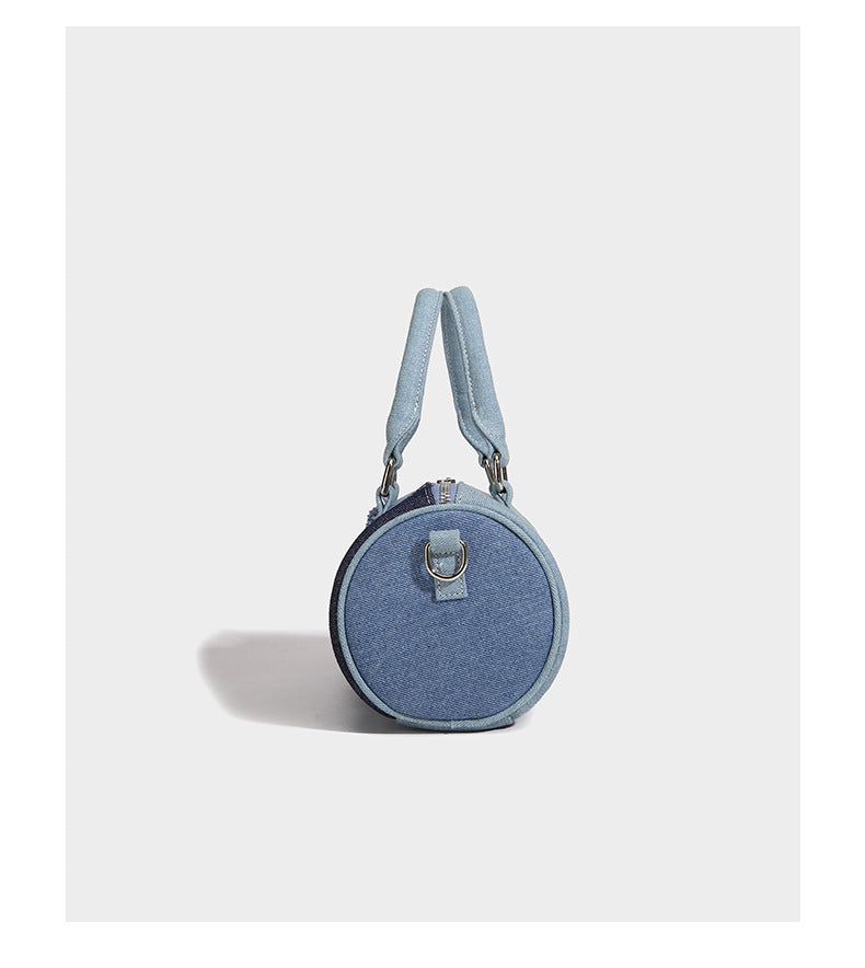 Mini barrel handbag in light and dark denim patchwork with frayed seam trim, dual top handles, top zip closure, and, detail