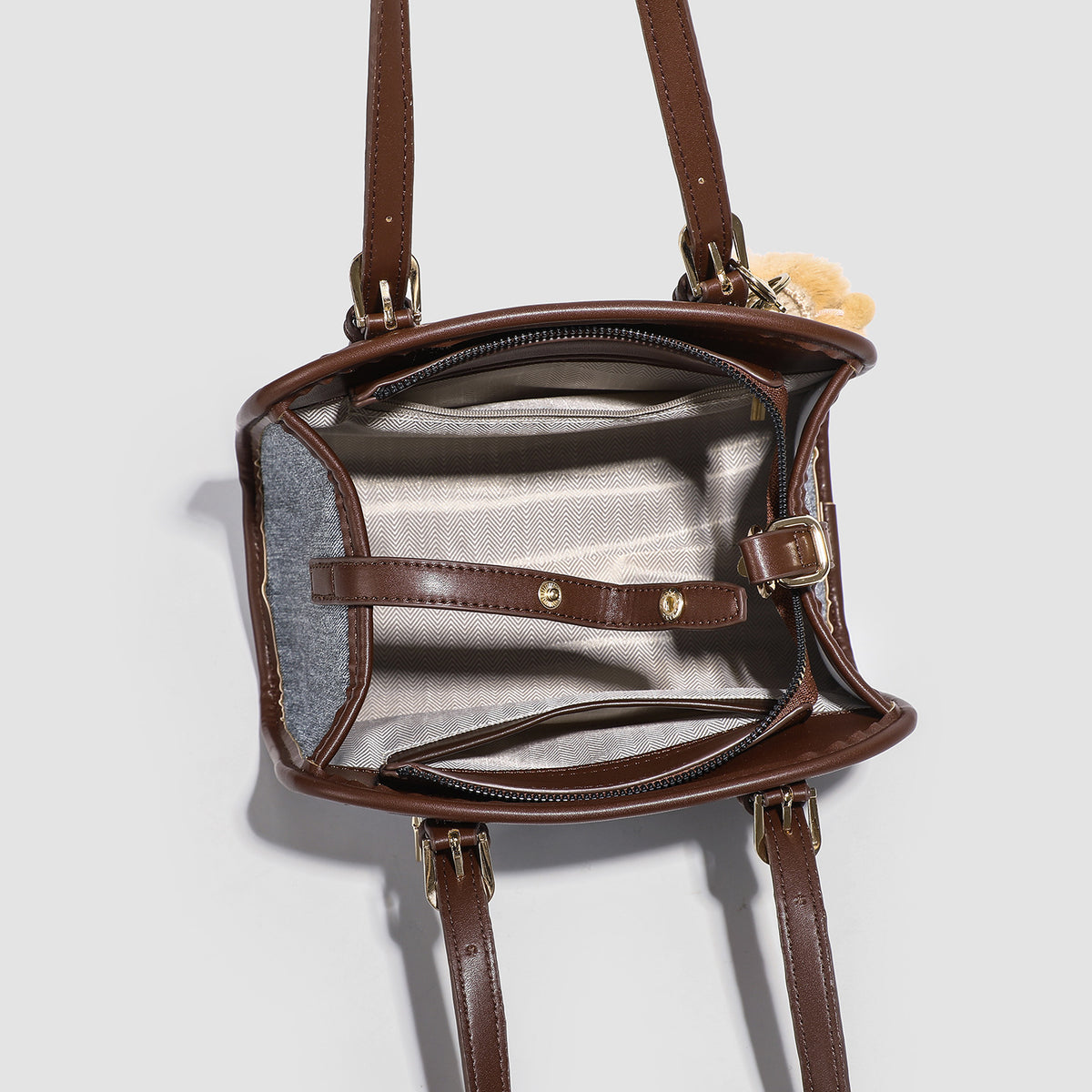 Small structured grey fabric shoulder bag with brown leather-look trim, gold-tone hardware, dual top handles, and detachable