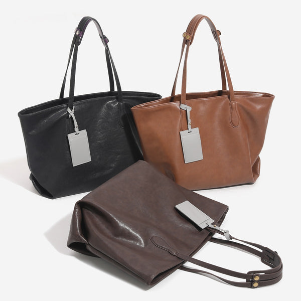 Large leather-look tote bag with trapezoid silhouette, double shoulder straps, and detachable hanging tag, front view