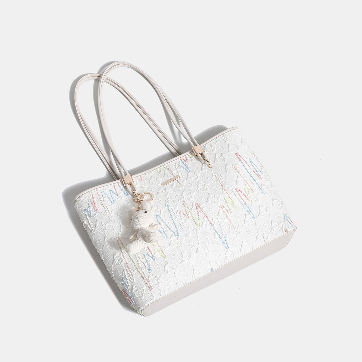 Off-white structured tote bag with dual shoulder straps, gold-tone hardware, and plush bear charm, detail view 4