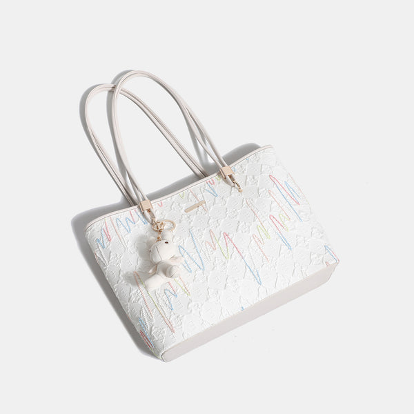 Off-white structured tote bag with dual shoulder straps, gold-tone hardware, and plush bear charm, detail view 4
