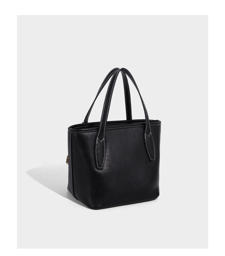 Compact structured bucket tote bag with pebbled textured finish, dual top handles, silver-tone lock hardware, and detachable