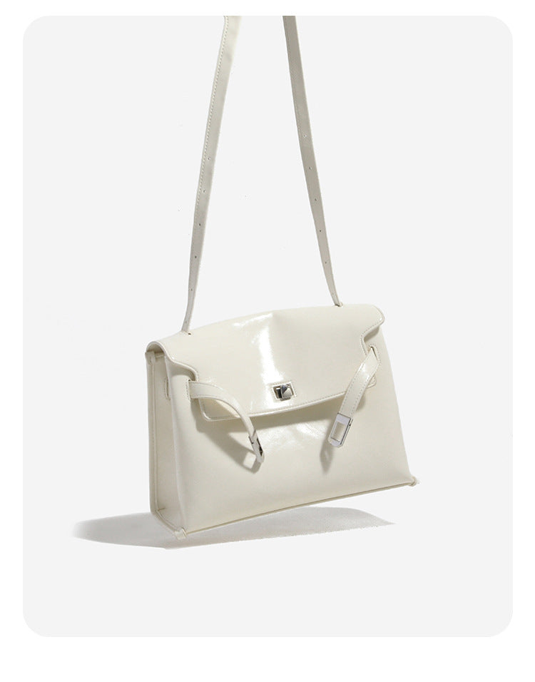 Structured rectangular flap shoulder bag in glossy leather-look finish with silver-tone turn-lock closure and adjustable
