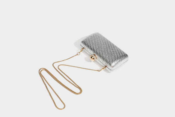 Small structured metallic woven-texture box clutch bag with jeweled kiss-lock dome clasp and slim gold chain strap, detail