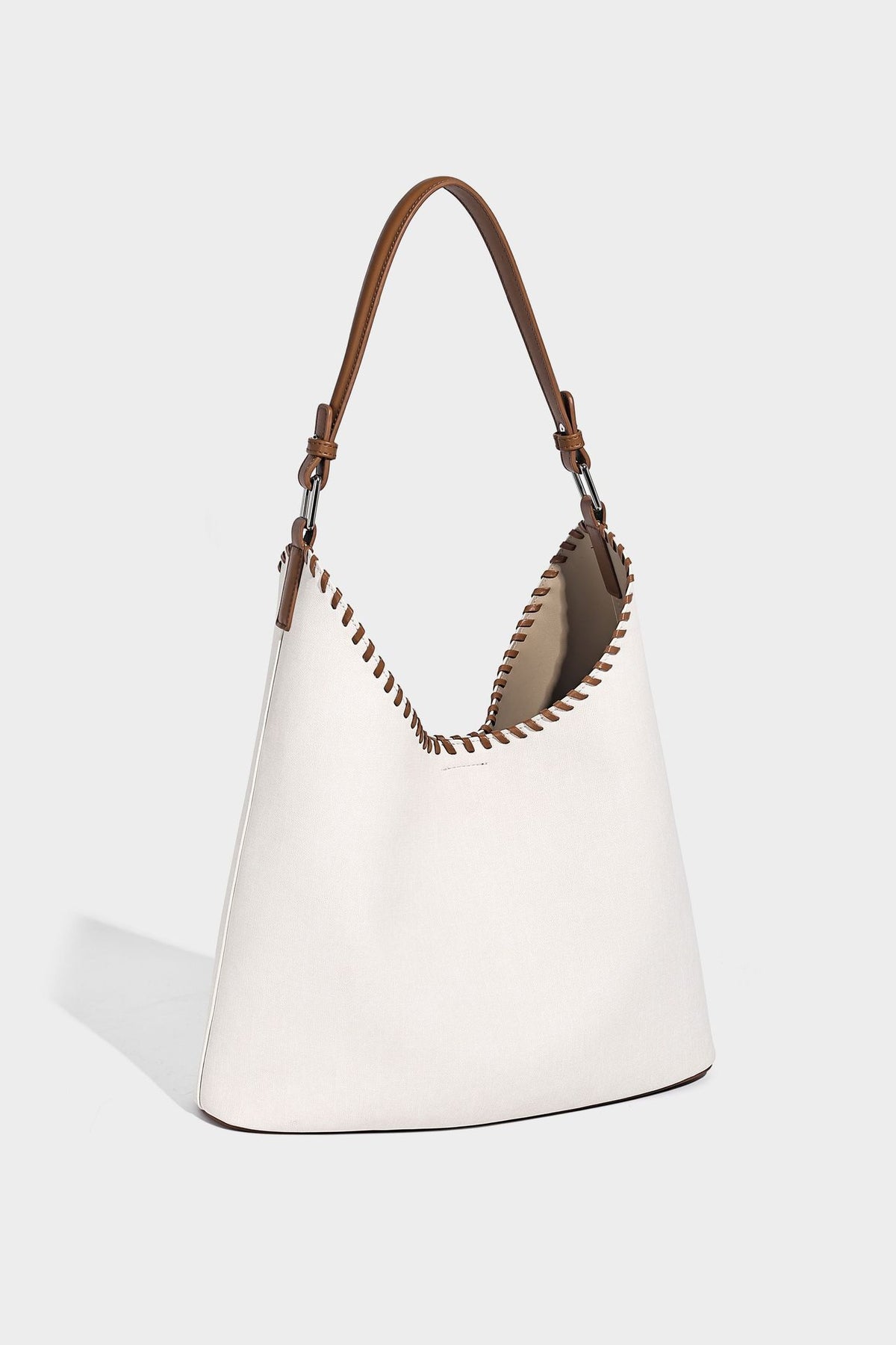 Denim-blue hobo tote with white leather-look shoulder strap, contrast whipstitch trim along curved open top, and silver-tone