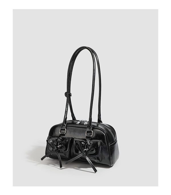 Kompakte glänzende Schultertasche aus Lederoptik mit vorderen Taschen mit Schleifen-Kordelzug, Reißverschluss oben, zwei Tragegriffen oben und Detail