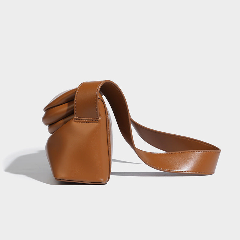Compact structured baguette shoulder bag with smooth leather-look finish, zip top, and adjustable silver-buckle strap, detail