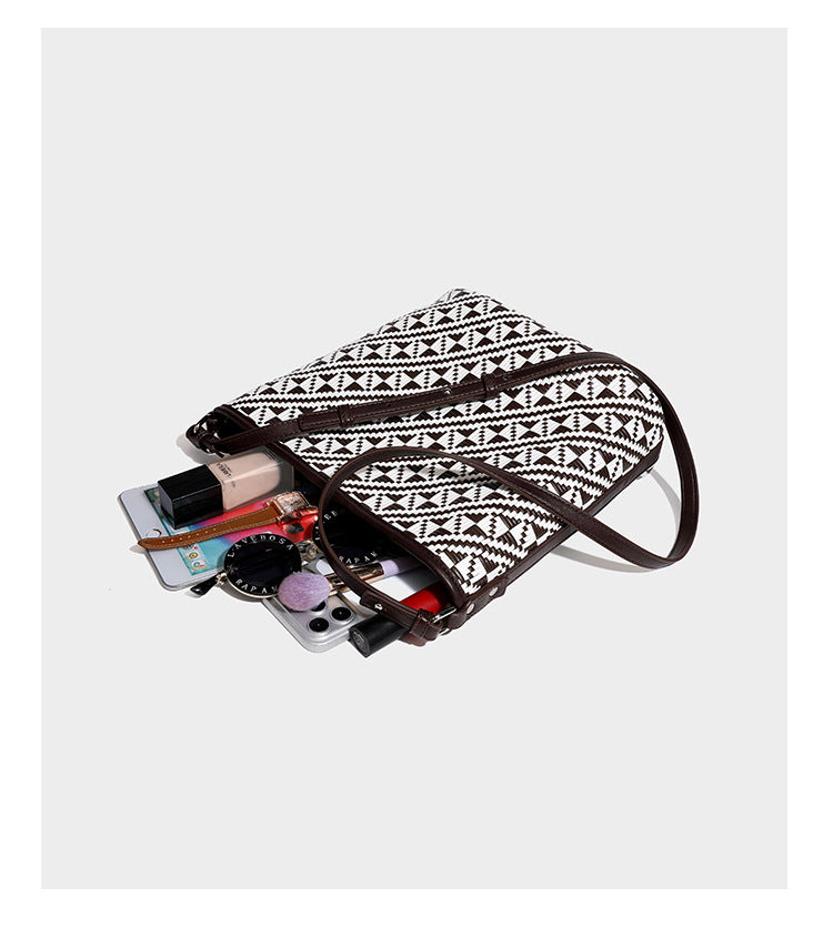 Geflochtene Schultertasche mit geometrischem Ethno-Muster, Besatz in dunkelbrauner Lederoptik, langem verstellbarem Träger und kleinem hängendem Reißverschluss