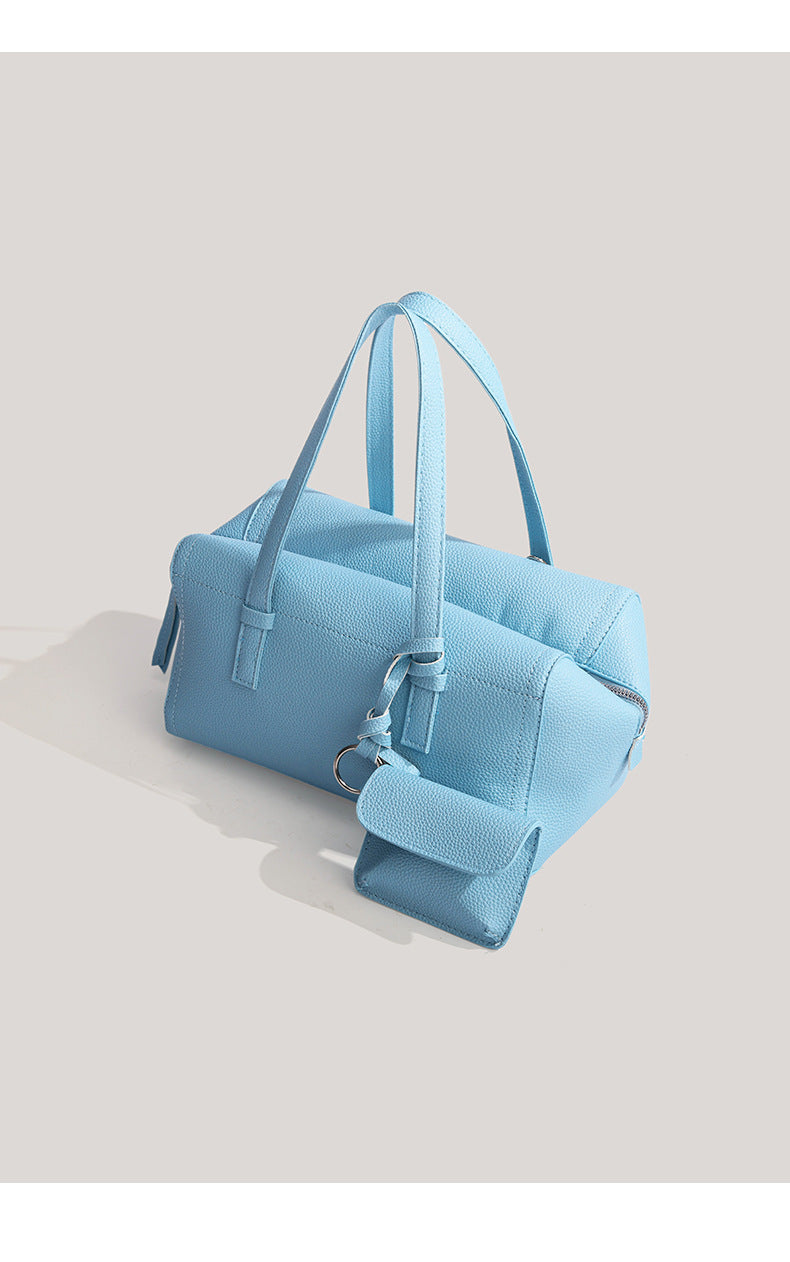 Light blue pebbled matte Boston tote bag with top handles, detachable shoulder strap, metal ring hardware, and matching mini