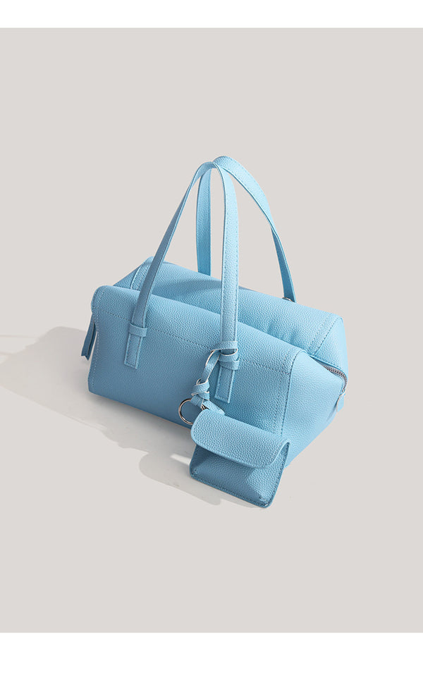 Light blue pebbled matte Boston tote bag with top handles, detachable shoulder strap, metal ring hardware, and matching mini