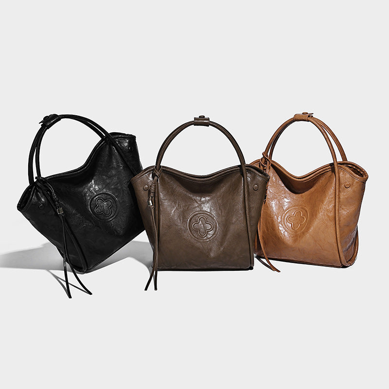 Glänzende Tote-Bag in geknautschter Lederoptik mit geprägtem Rundemblem, Quastenverschluss, zwei Tragegriffen und abnehmbarem