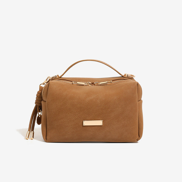 Compact boxy mini handbag with matte pebbled finish, dual top zipper, short top handle, side tassel charm, and gold-tone