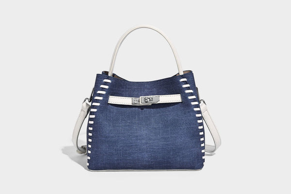 Formstabile Beuteltasche aus Denim mit weißem Zierstich-Besatz, silberfarbenem Drehverschluss, kurzen Henkeln und einem langen verstellbaren