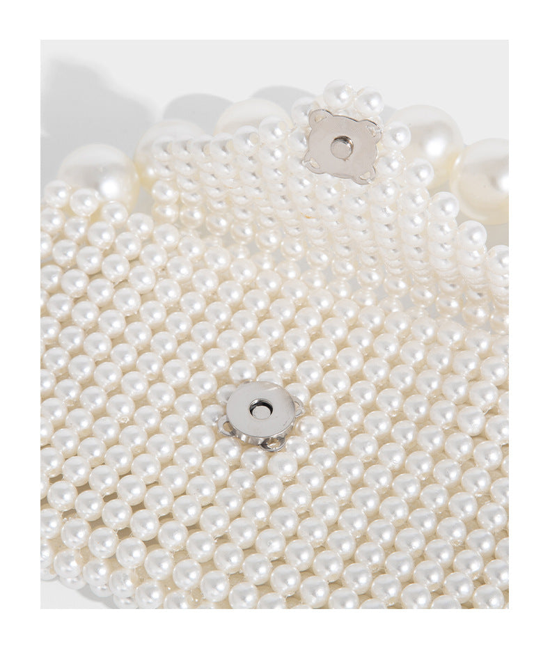Small structured triangle clutch bag covered in glossy pearl beads with an arched pearl top handle and silver snap closure