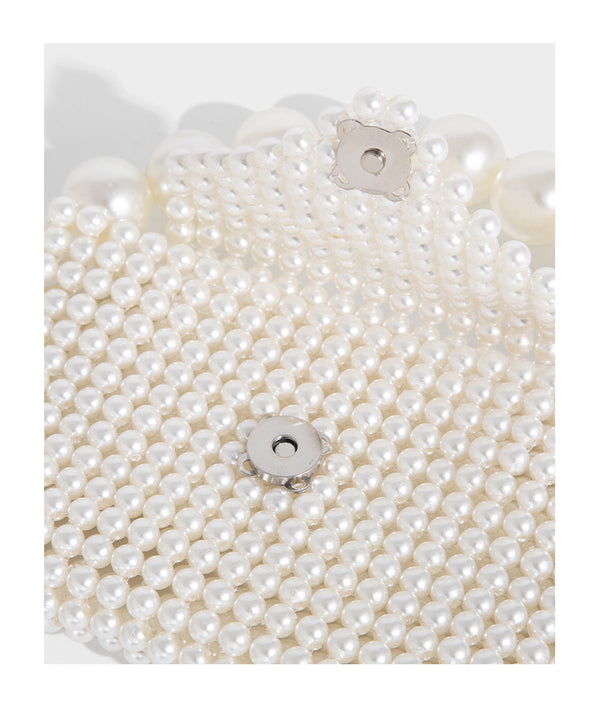 Small structured triangle clutch bag covered in glossy pearl beads with an arched pearl top handle and silver snap closure