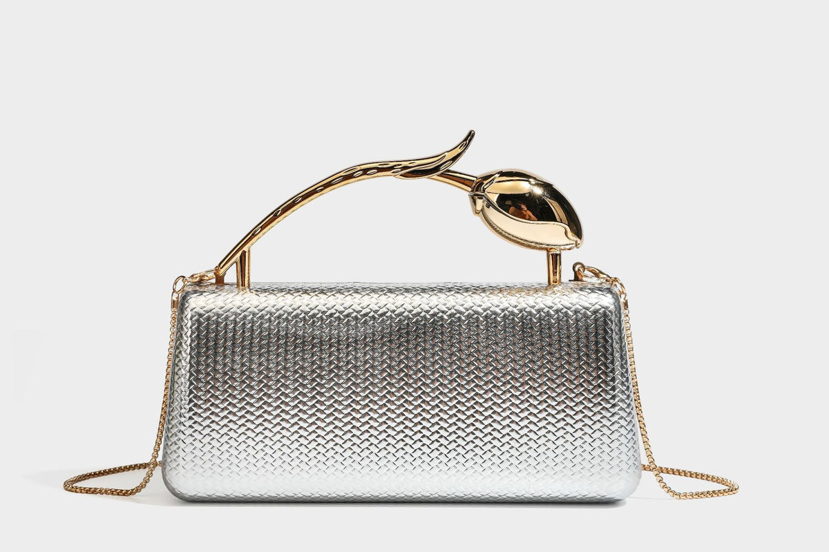 Structured rectangular metallic woven clutch bag with sculptural gold-tone leaf top handle and detachable chain strap, detail