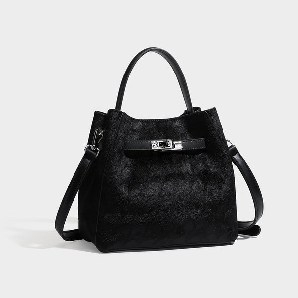 Small structured bucket satchel in embossed velvet-texture fabric with silver turn-lock hardware, rounded top handle, and