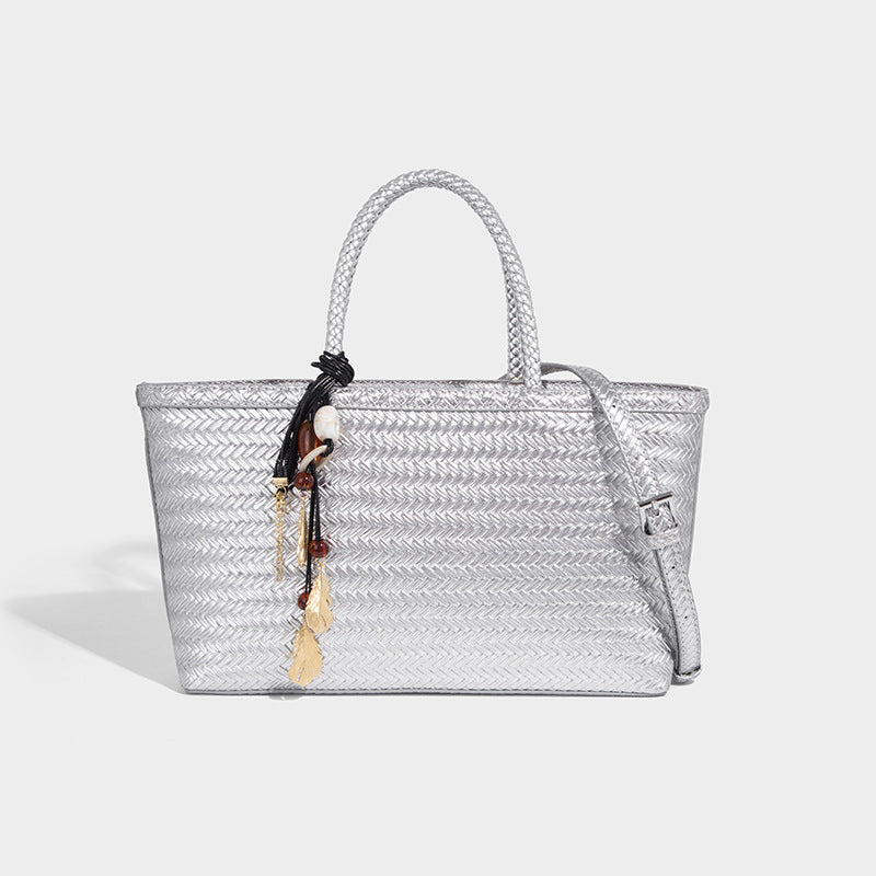 Structured woven-texture tote bag with brown braided top handles, decorative tassel charm, and detachable shoulder strap