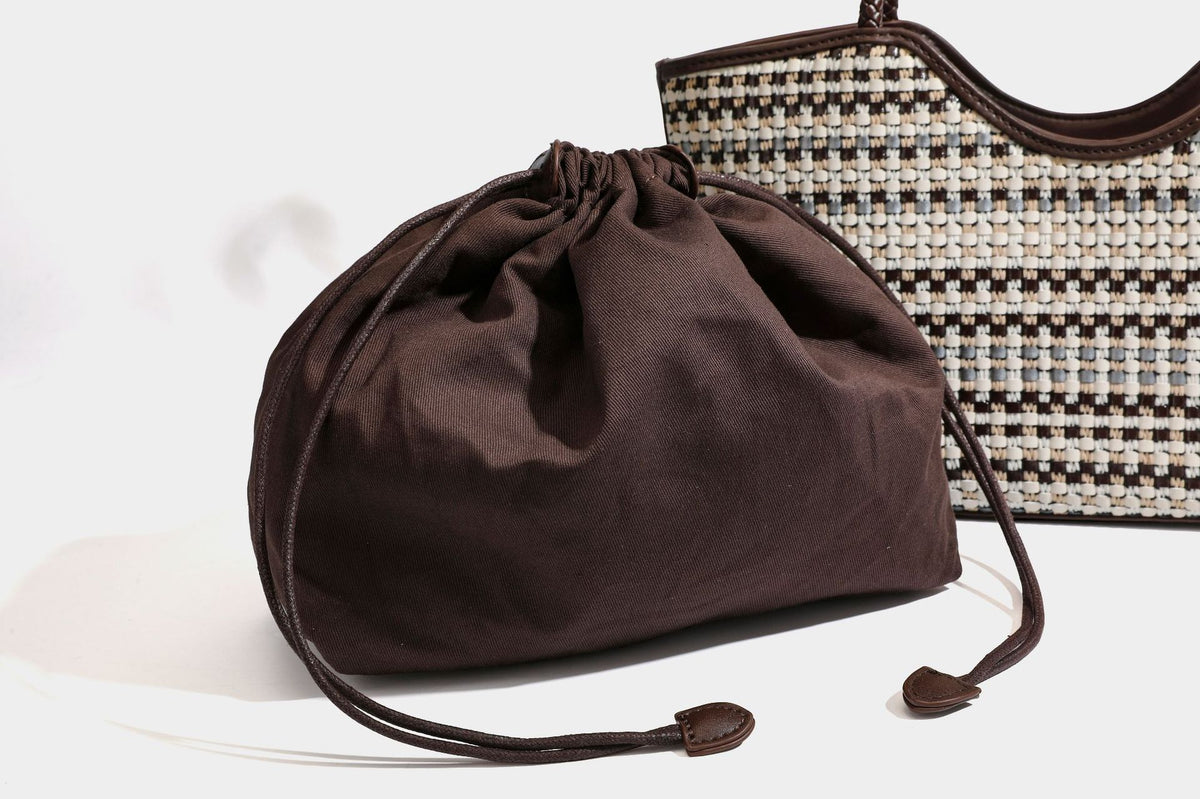 Large woven checker-pattern tote bag with dark braided shoulder straps, leather-look trim, and drawstring side ties, detail