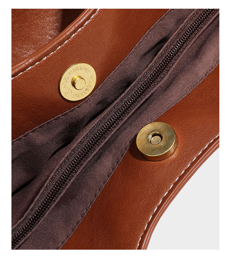 Structured smooth leather-look tote bag with long shoulder strap, gold-tone hardware, and hanging tassel-coin charm, detail