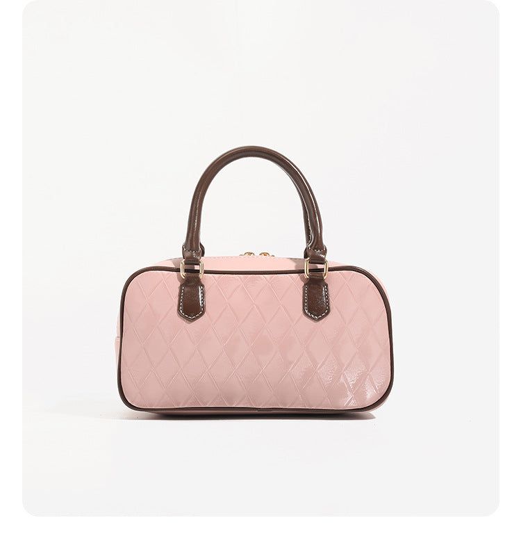 Blush pink quilted bowling barrel bag with dark brown leather-look trim and handles, baseball bat and ball charm, gold-tone