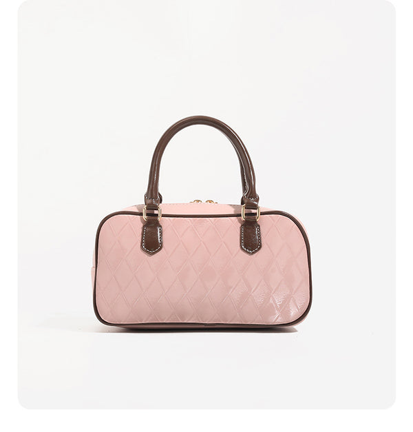 Blush pink quilted bowling barrel bag with dark brown leather-look trim and handles, baseball bat and ball charm, gold-tone
