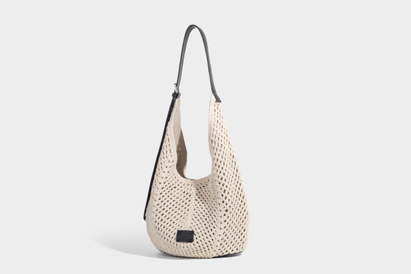 Cream openwork crochet hobo bag with black leather-look strap and trim patch accent, slouchy teardrop silhouette, detail view