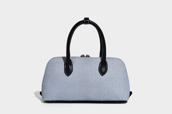 Compact structured satchel in light blue denim-look fabric with black leather-look trim, silver turn-lock closure, rolled
