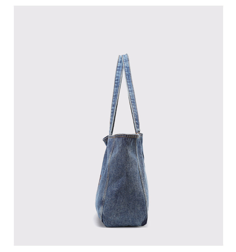 Große gewaschene blaue Denim-Tote-Bag mit handschriftähnlichem Grafikprint, kontrastierenden orangefarbenen Nähten und langem Stoffschulterriemen