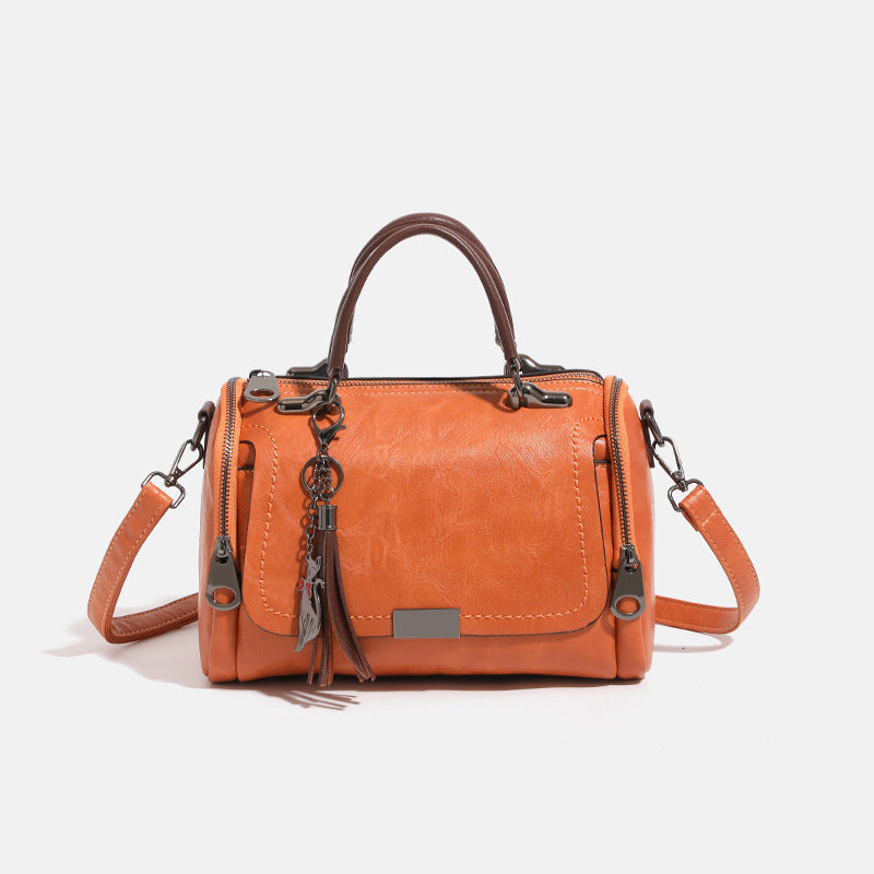 Compact structured barrel bag in distressed leather-look finish with dual top handles, detachable crossbody strap, front zip