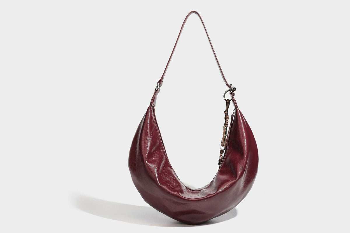 Lässig fallende Hobo-Schultertasche in Halbmondform mit glänzender, geknautschter Lederoptik, schmalem Riemen, silberfarbenen Ringbeschlägen und
