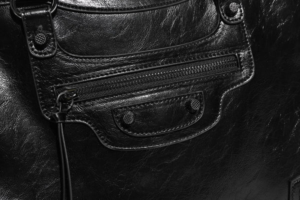Large structured leather-look tote bag with front zip pocket, moto hardware accents, and long double shoulder straps, detail