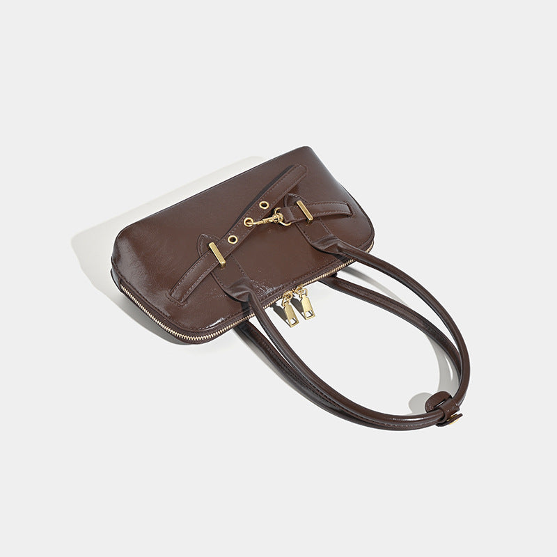 Small structured glossy leather-look shoulder bag with gold-tone buckle hardware and twin top handles, detail view 4