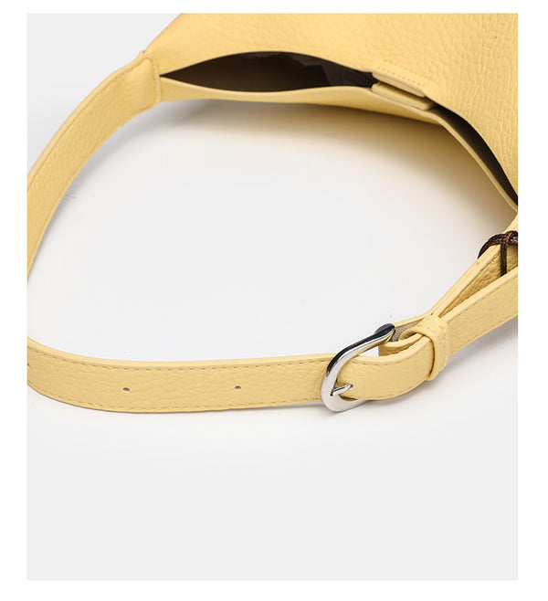 Slouchy hobo shoulder bag in pale yellow pebbled texture with woven charm, adjustable strap, matching zip pouch, and, detail