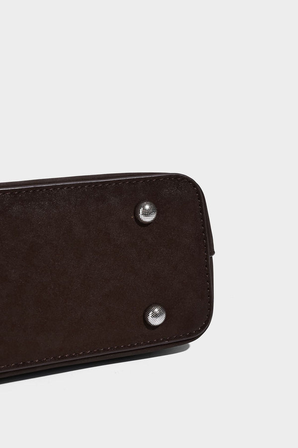 Structured trapezoid shoulder tote in dark brown matte suede-look finish with dual straps, wraparound belt bands
