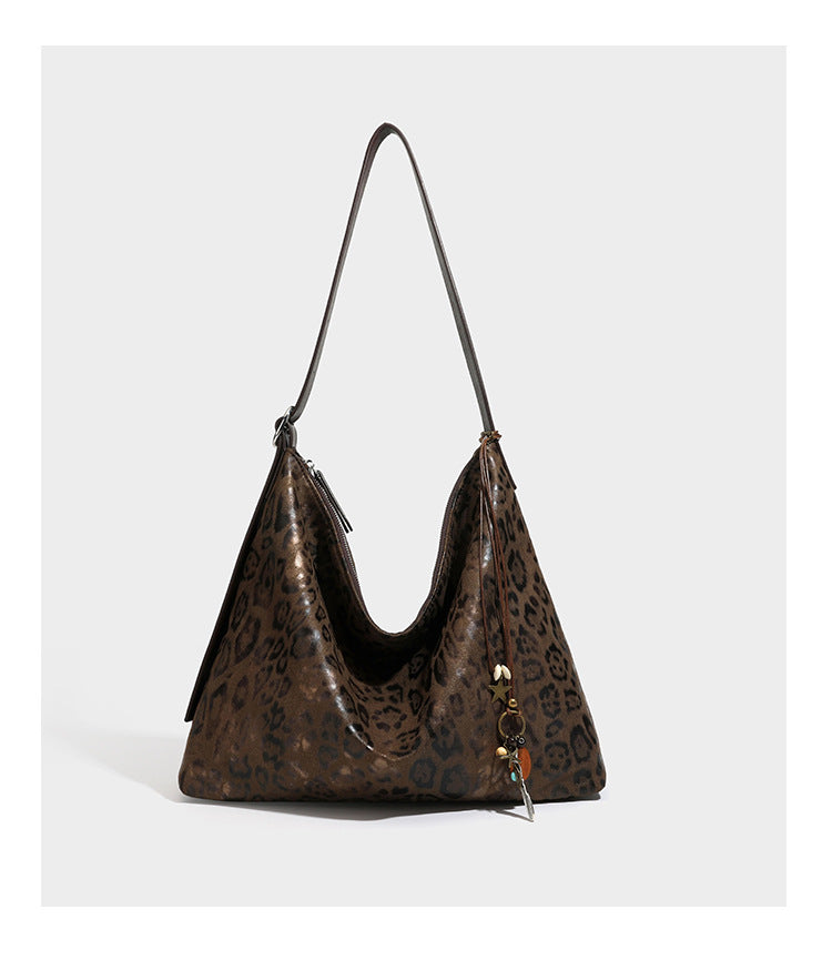 Slouchy leopard print hobo shoulder bag with glossy coated finish, top zipper closure, dark brown trim, and dangling charm