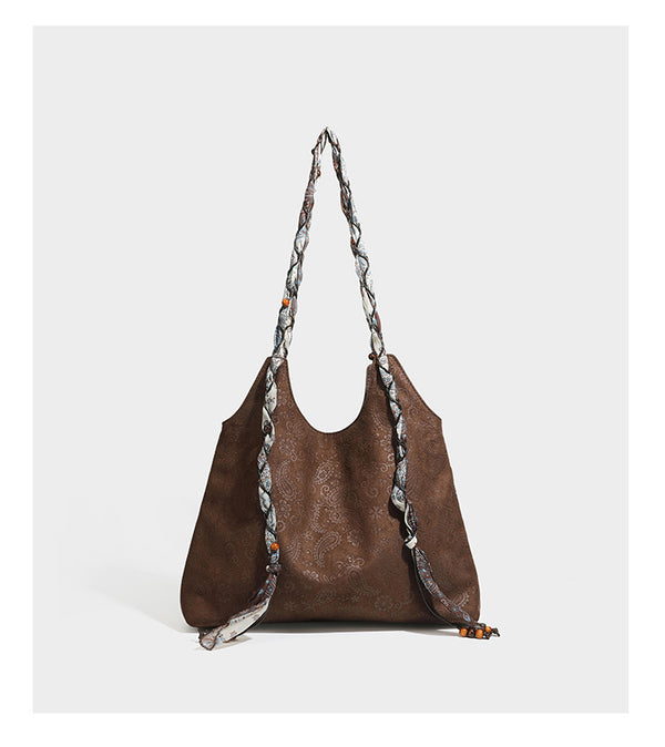 Slouchy paisley-embossed suede-look shoulder tote bag with braided patterned fabric straps and wood bead accents, detail view