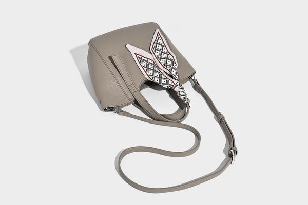 Structured pebbled leather-look tote bag with detachable scarf tie, dual top handles, and adjustable crossbody strap, detail