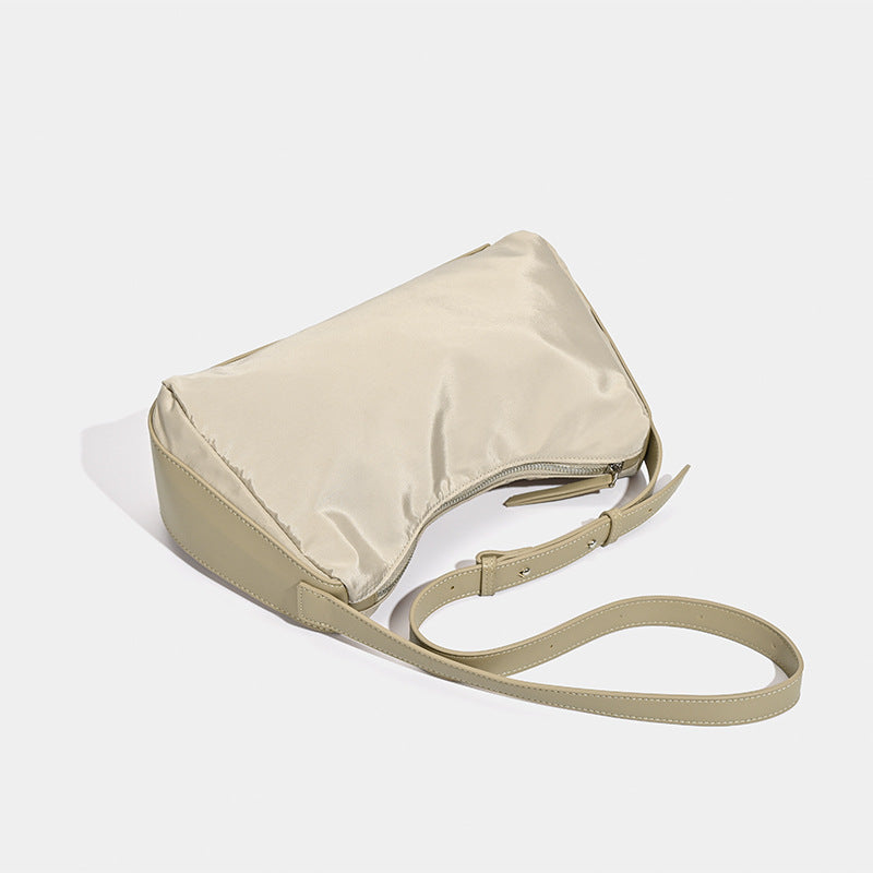 Soft crescent shoulder bag in smooth sheen nylon with contrast leather-look trim, slim adjustable strap, and top zip closure