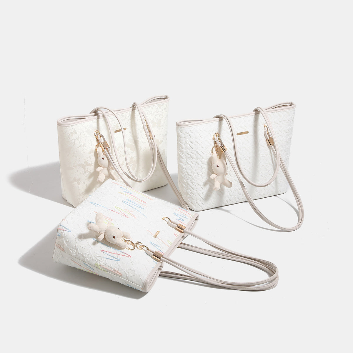 Off-white structured tote bag with dual shoulder straps, gold-tone hardware, and plush bear charm, detail view 2