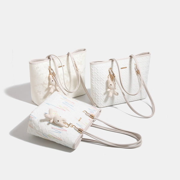 Off-white structured tote bag with dual shoulder straps, gold-tone hardware, and plush bear charm, detail view 2