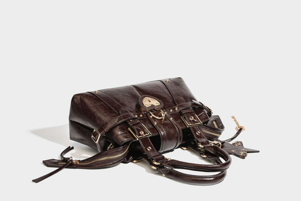 Structured leather-look satchel bag with heart padlock charm, star charm, gold-tone buckle hardware, dual top handles, and