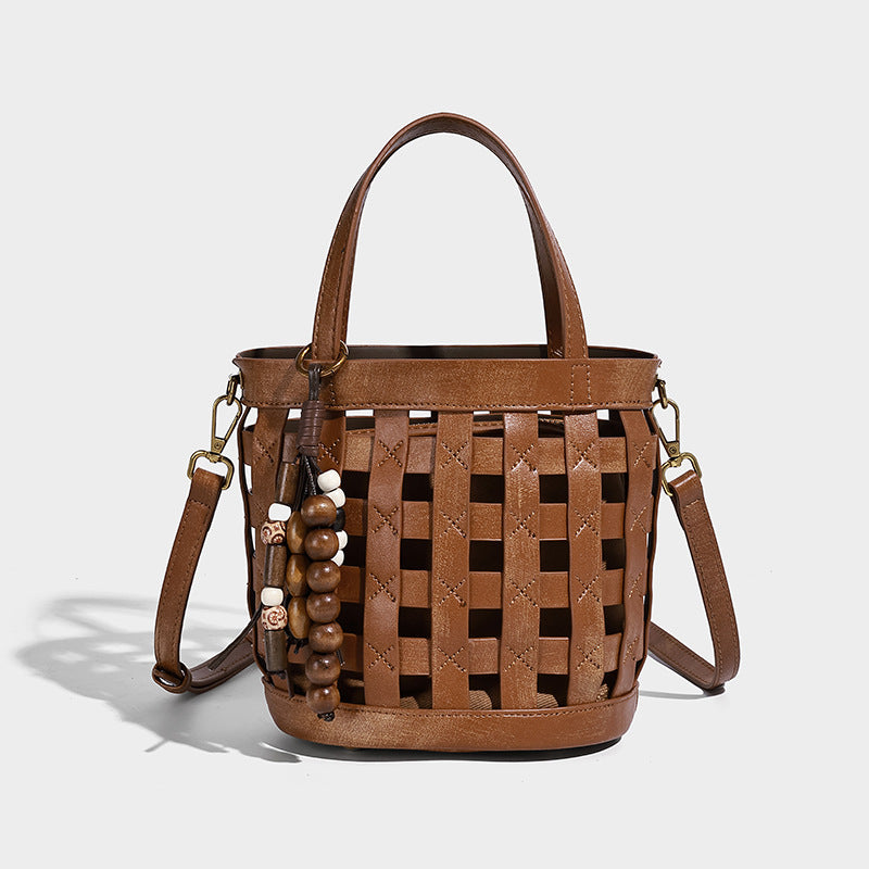 Small woven lattice bucket bag in brown leather-look finish with beaded tassel charm, dual top handles, and detachable