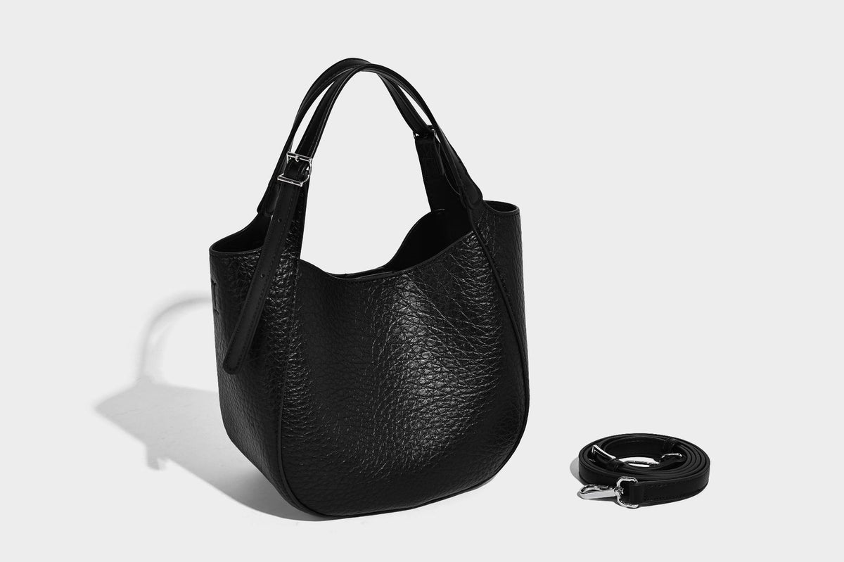Small pebbled half-moon shoulder bag with dual top handles, detachable crossbody strap, and silver-tone hardware, detail view
