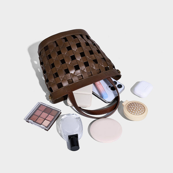 Small woven lattice bucket bag in brown leather-look finish with beaded tassel charm, dual top handles, and detachable